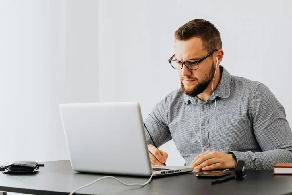Hombre estudiando con laptop y auriculares, representando el bachillerato acelerado online en Ecuador con educación flexible y acompañamiento
