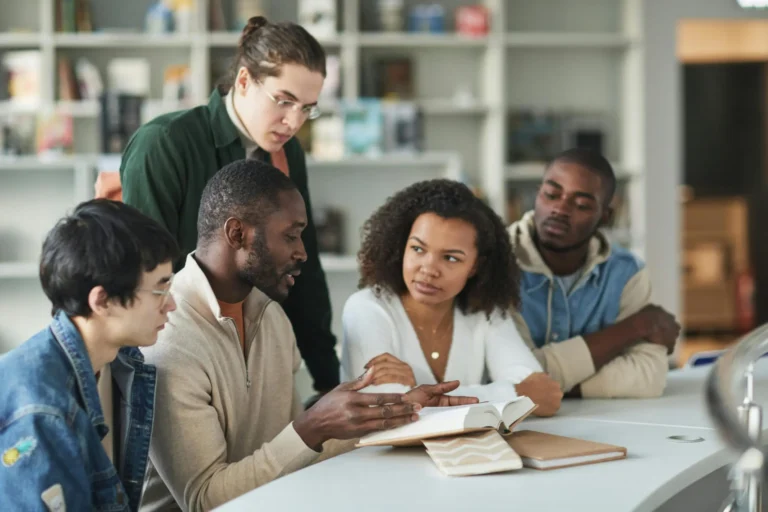 Grupo de estudiantes trabajando juntos en biblioteca, representando el ciclo básico acelerado online con educación virtual certificada