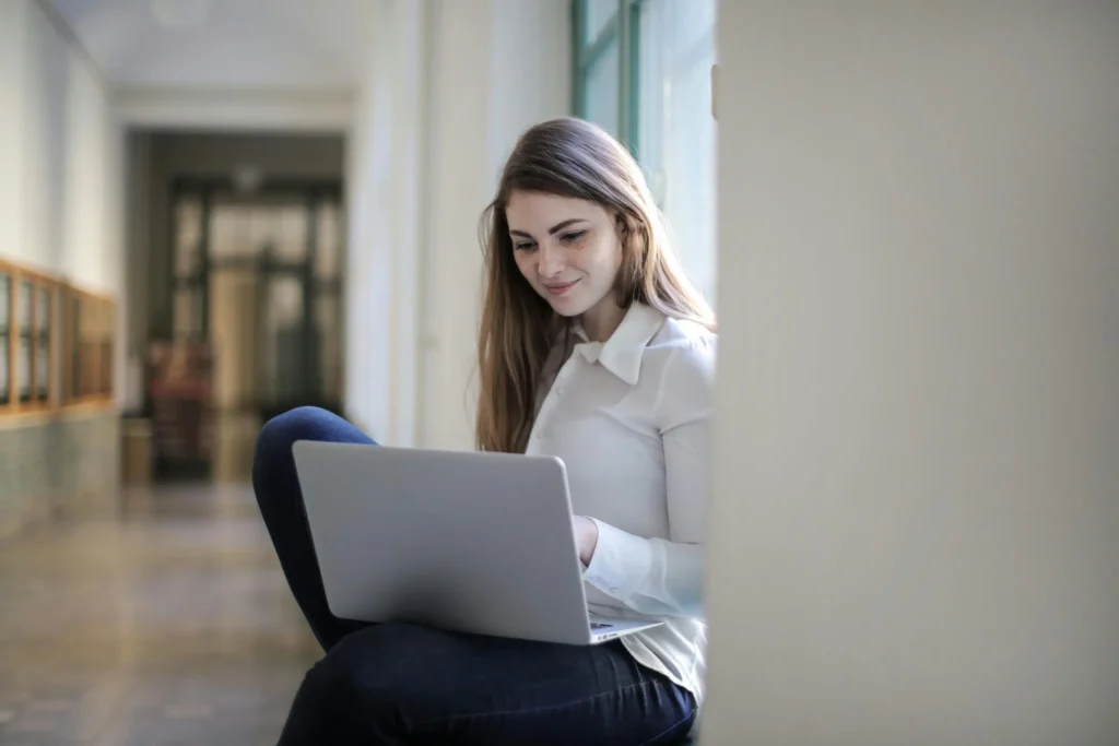 Estudiante con laptop sonriendo en pasillo, representando a Edynova como institución innovadora en educación online en Ecuador